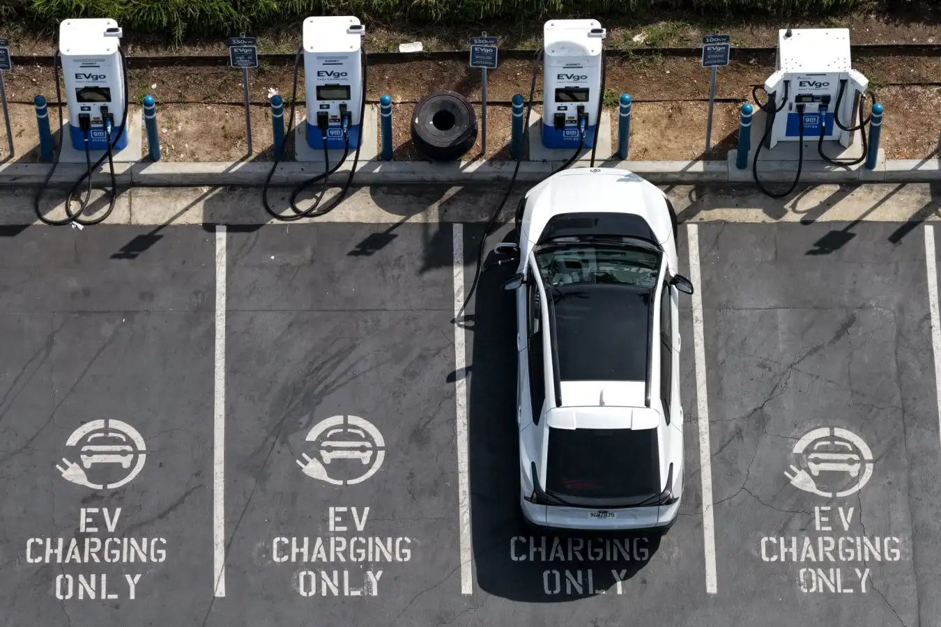 MONROVIA, CALIFORNIA - MARCH 30: In an aerial view, an electric vehicle charges at an EVgo electric charger on March 30, 2026, in Monrovia, California. As gas prices surge amid the war in Iran, online automotive resource Edmunds reported a 22% increase in searches for electric vehicles during the week of March 2, as motorists look for ways to avoid high fuel costs. (Photo by Justin Sullivan/Getty Images)