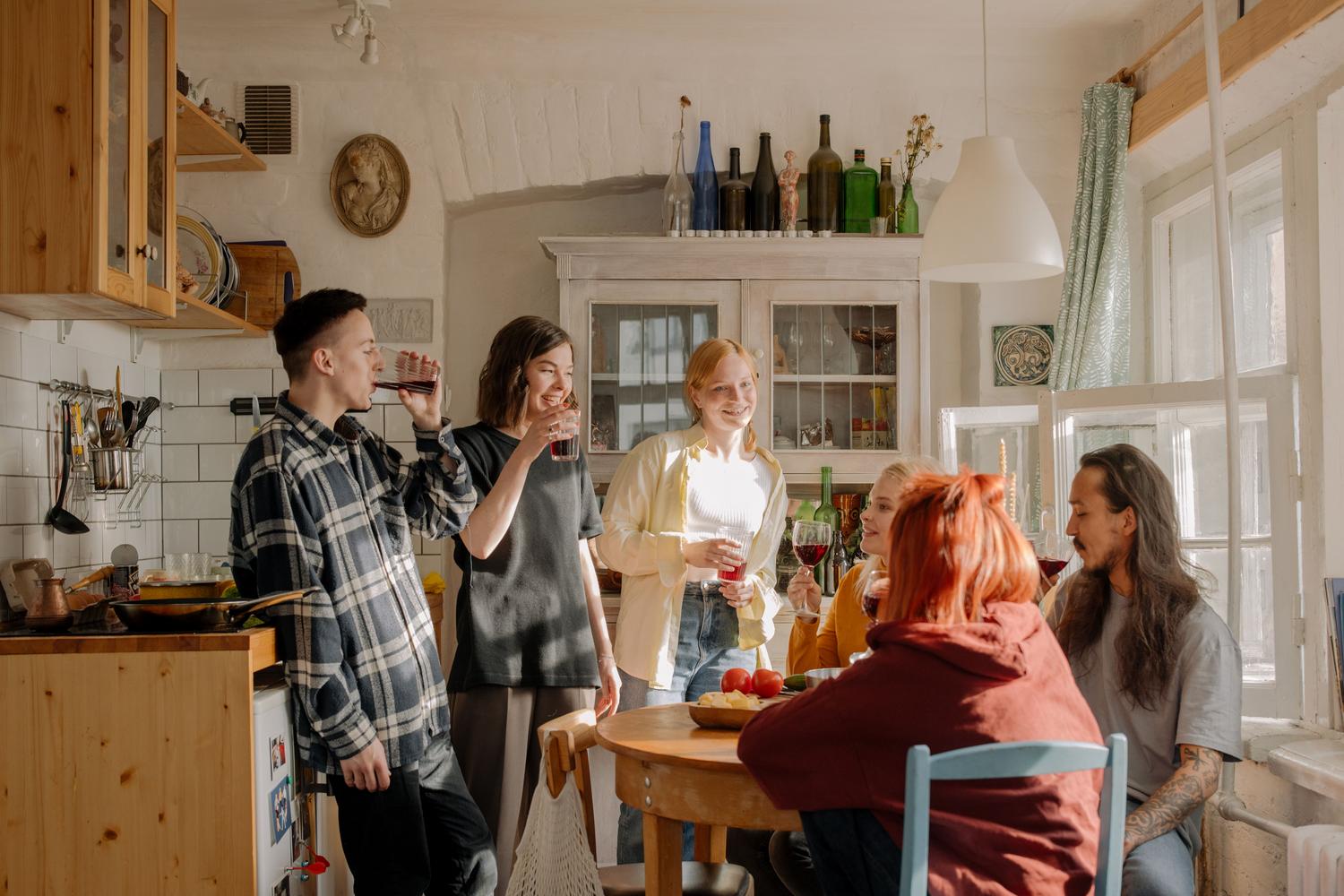 Draugu grupa, kas bauda saviesīgu sapulci koplietošanas dzīvokļa virtuvē, ideāls konteksts grupu izdevumu lietotnēm