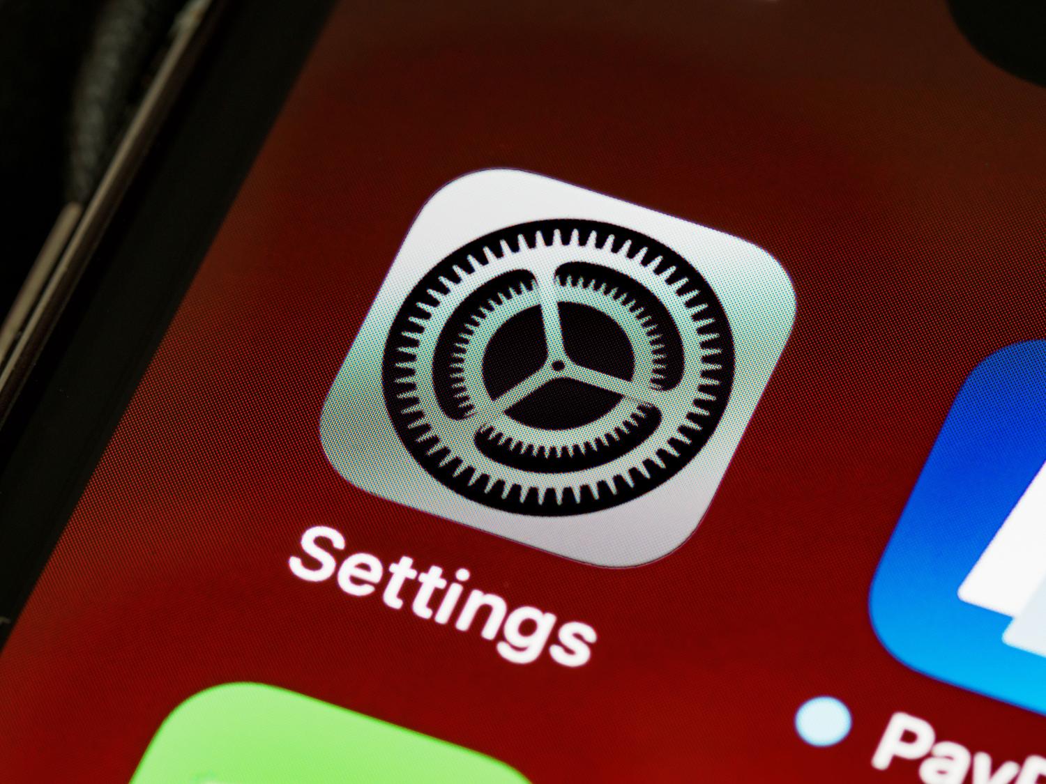 Ikonas Iestatījumi makroattēls iPhone ekrānā, centrālais punkts privātuma un fotoattēlu atļauju pārvaldībai.