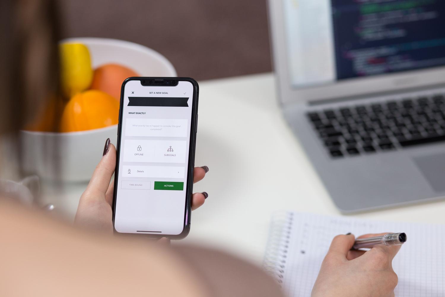 Darba mērķu plānošana, izmantojot iPhone un klēpjdatoru uz moderna galda. Darba mērķu plānošana, izmantojot iPhone un klēpjdatoru uz moderna galda.