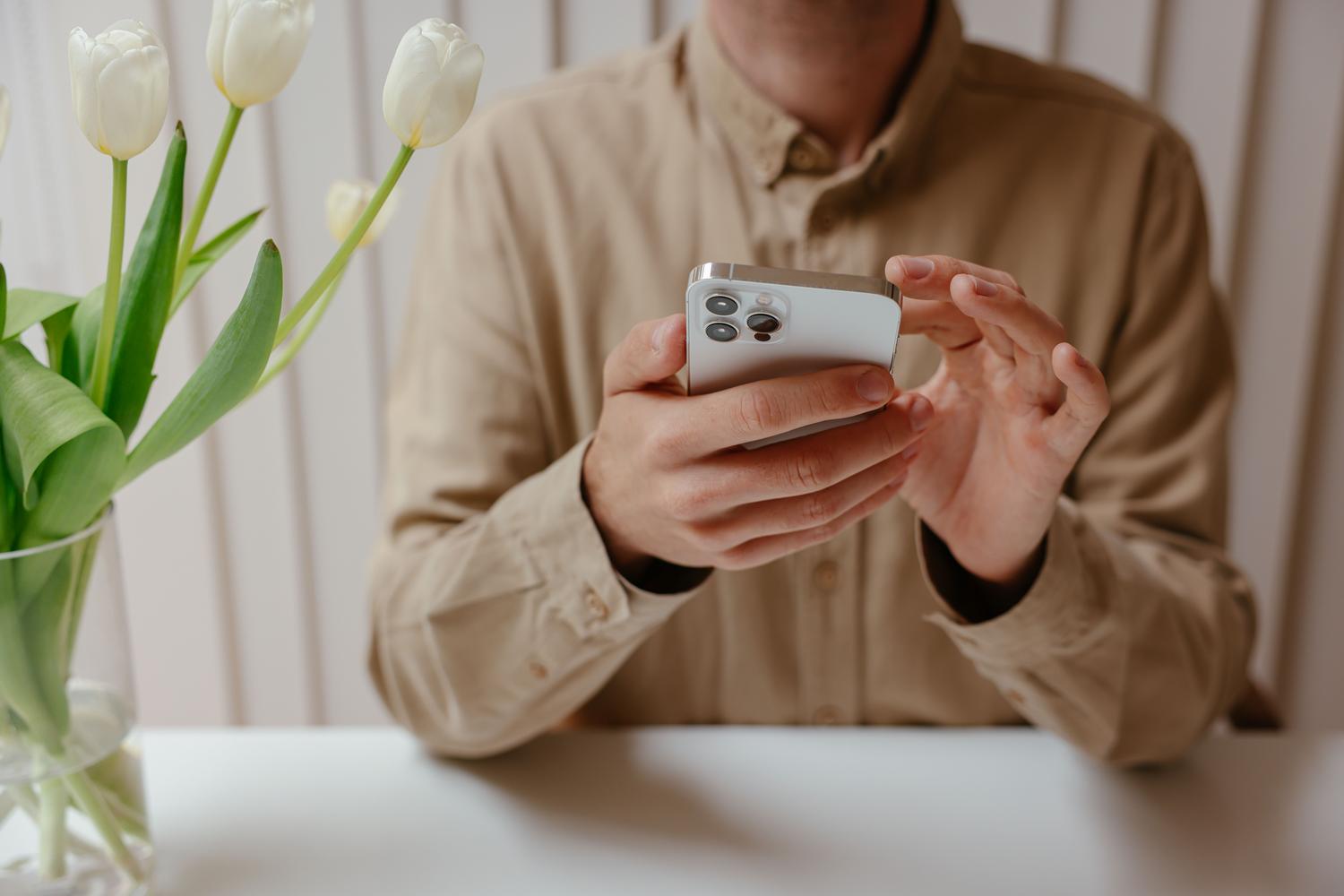 Personas tuvplāns, kas mijiedarbojas ar iPhone spilgtā, minimālistiskā biroja vidē. Personas tuvplāns, kas mijiedarbojas ar iPhone spilgtā, minimālistiskā biroja vidē.