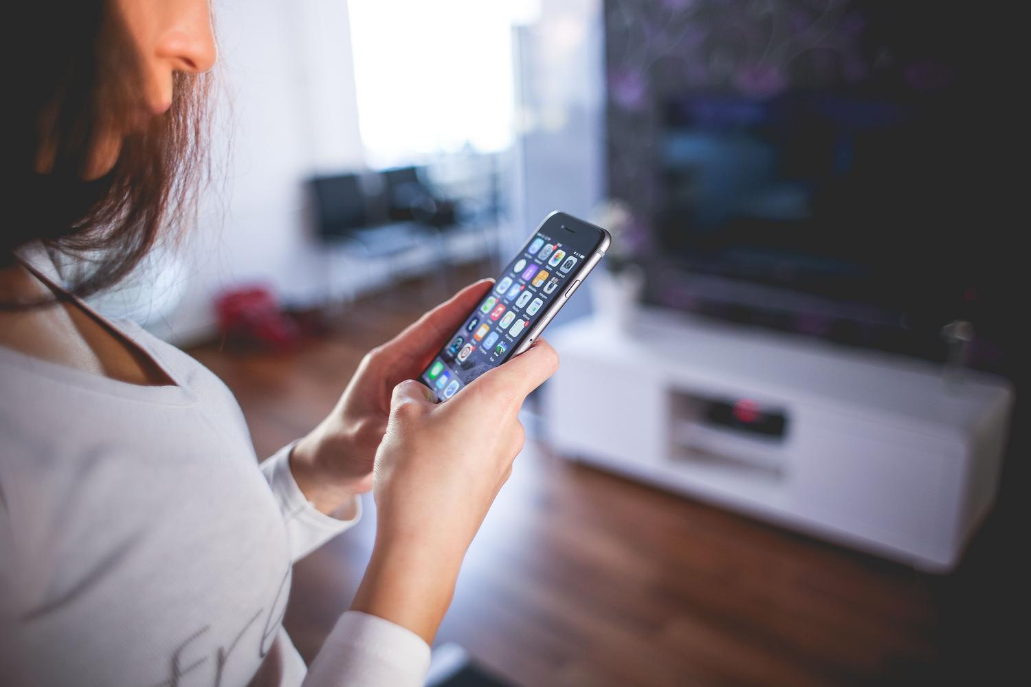 Sieviete izmanto savu viedtālruni mājās un pārvalda iCloud dublējumu, lai atgūtu ziņojumus