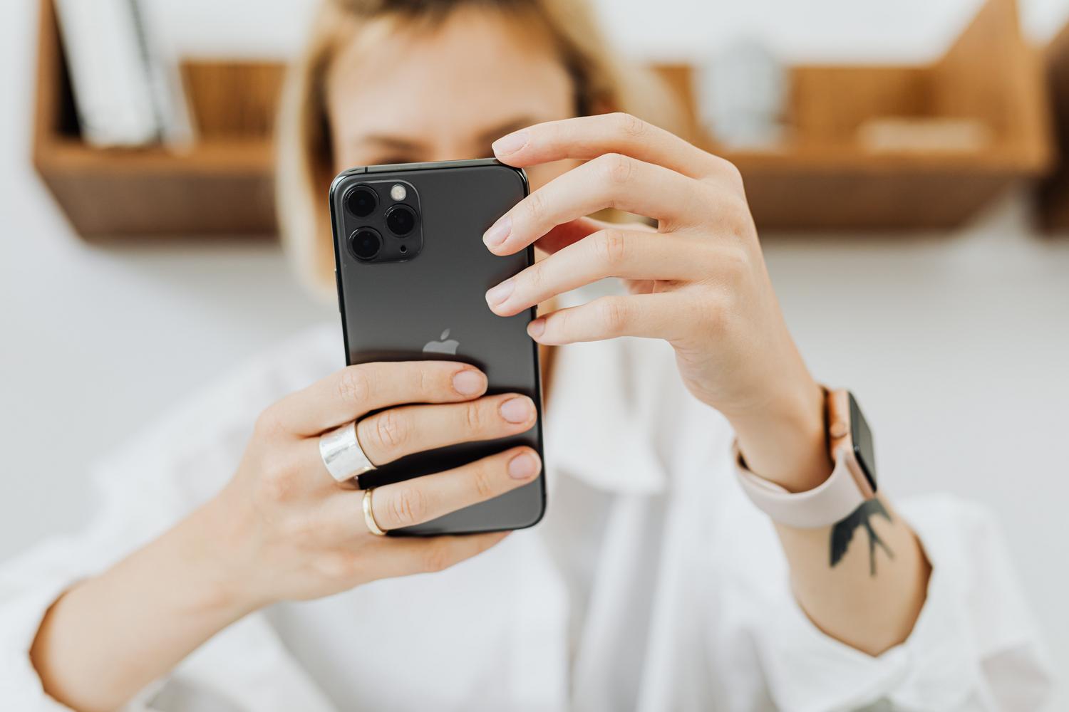Sieviete modernā mājas vidē tur rokās iPhone. Sieviete modernā mājas vidē tur rokās iPhone.