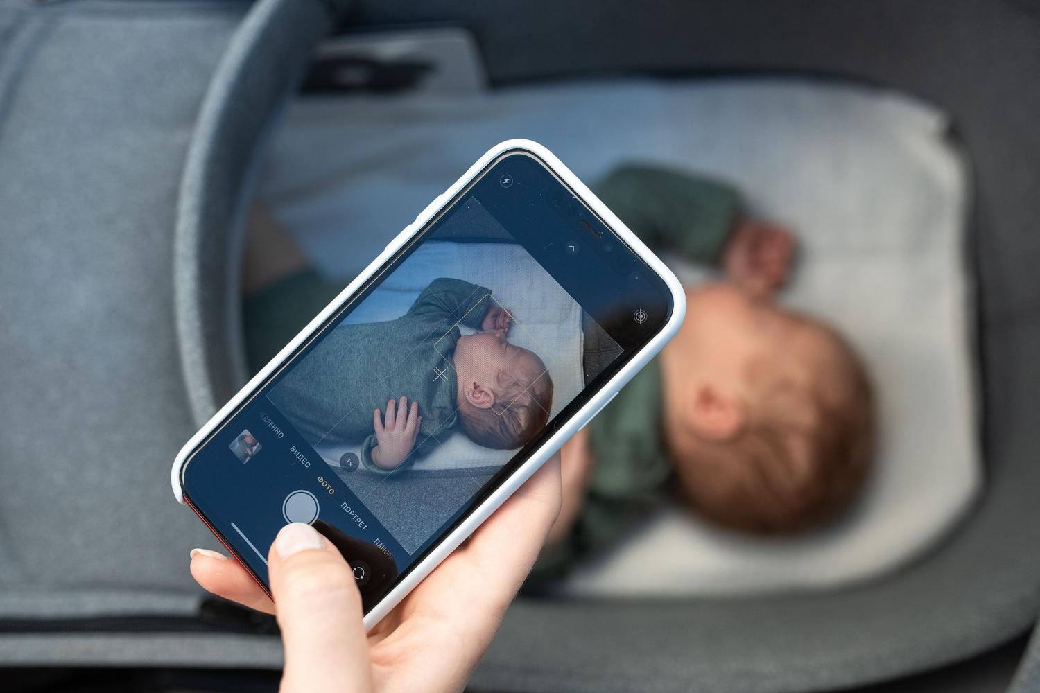 Izmantojot viedtālruni kā mazuļa monitoru, lai uzraudzītu jaundzimušo, kas guļ savā gultiņā.