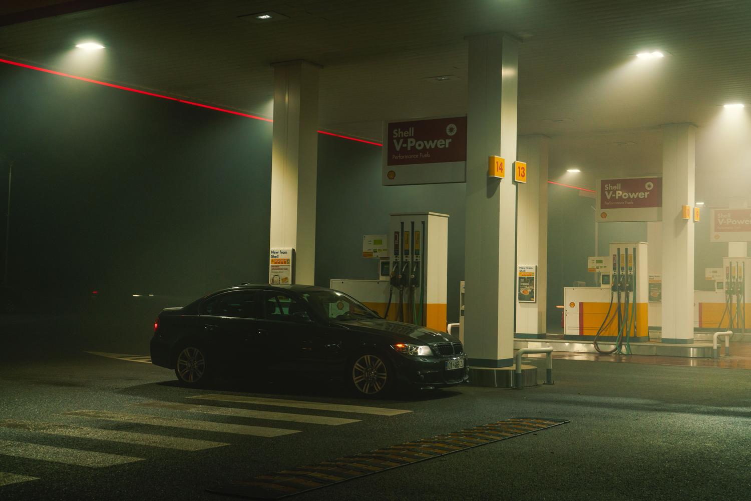 Moderna automašīna, kas novietota pilsētas degvielas uzpildes stacijā, kas ir apgaismota naktī, saturam piešķirot kinematogrāfisku un mūsdienīgu estētiku. Moderna automašīna, kas novietota pilsētas degvielas uzpildes stacijā, kas ir apgaismota naktī, saturam piešķirot kinematogrāfisku un mūsdienīgu estētiku.