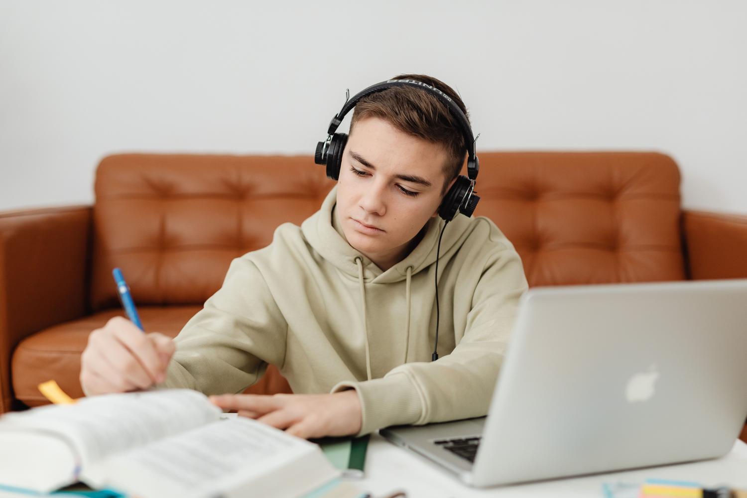 Koncentrēts students, kurš mācās ar austiņām, atspoguļo vides trokšņu izmantošanu, lai uzlabotu fokusu.