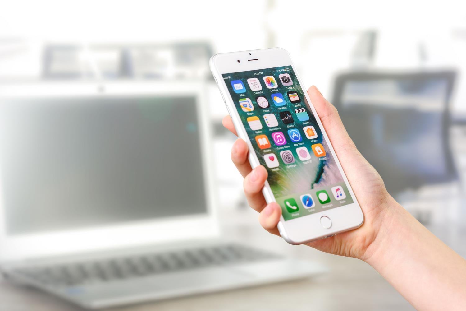Tuvplāns ar roku, kas tur iPhone, kurā redzamas dažādas profesionālas lietojumprogrammas Tuvplāns ar roku, kas tur iPhone, kurā redzamas dažādas profesionālas lietojumprogrammas