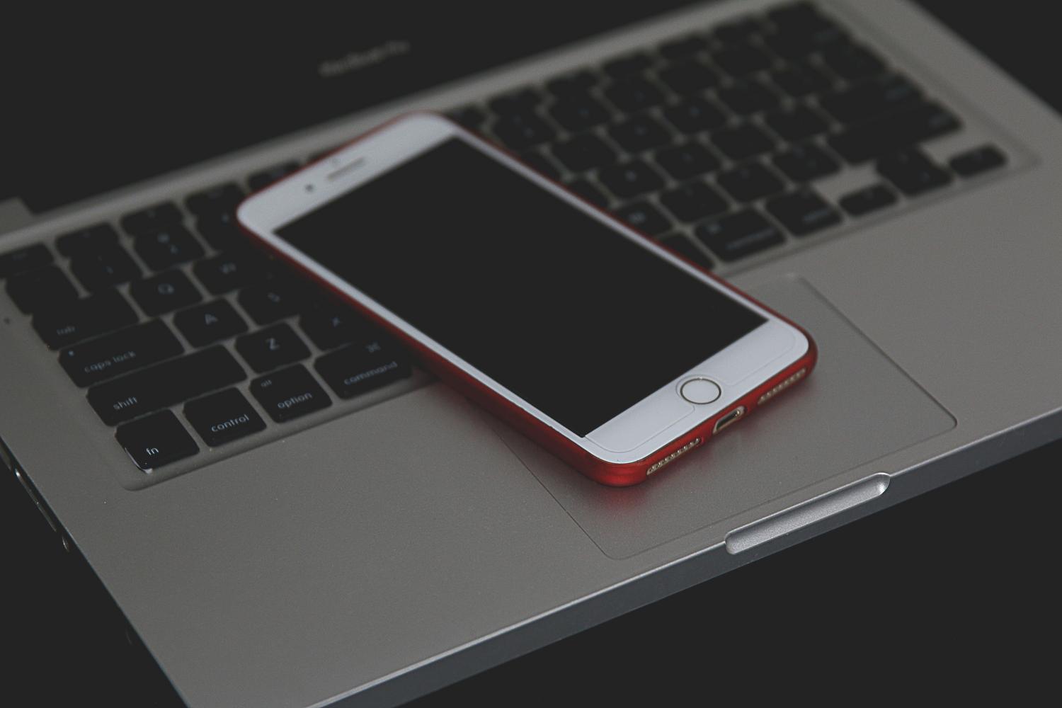 iPhone blakus klēpjdatoram, kas ilustrē sinhronizāciju starp ierīcēm, lai pabeigtu CV iPhone blakus klēpjdatoram, kas ilustrē sinhronizāciju starp ierīcēm, lai pabeigtu CV