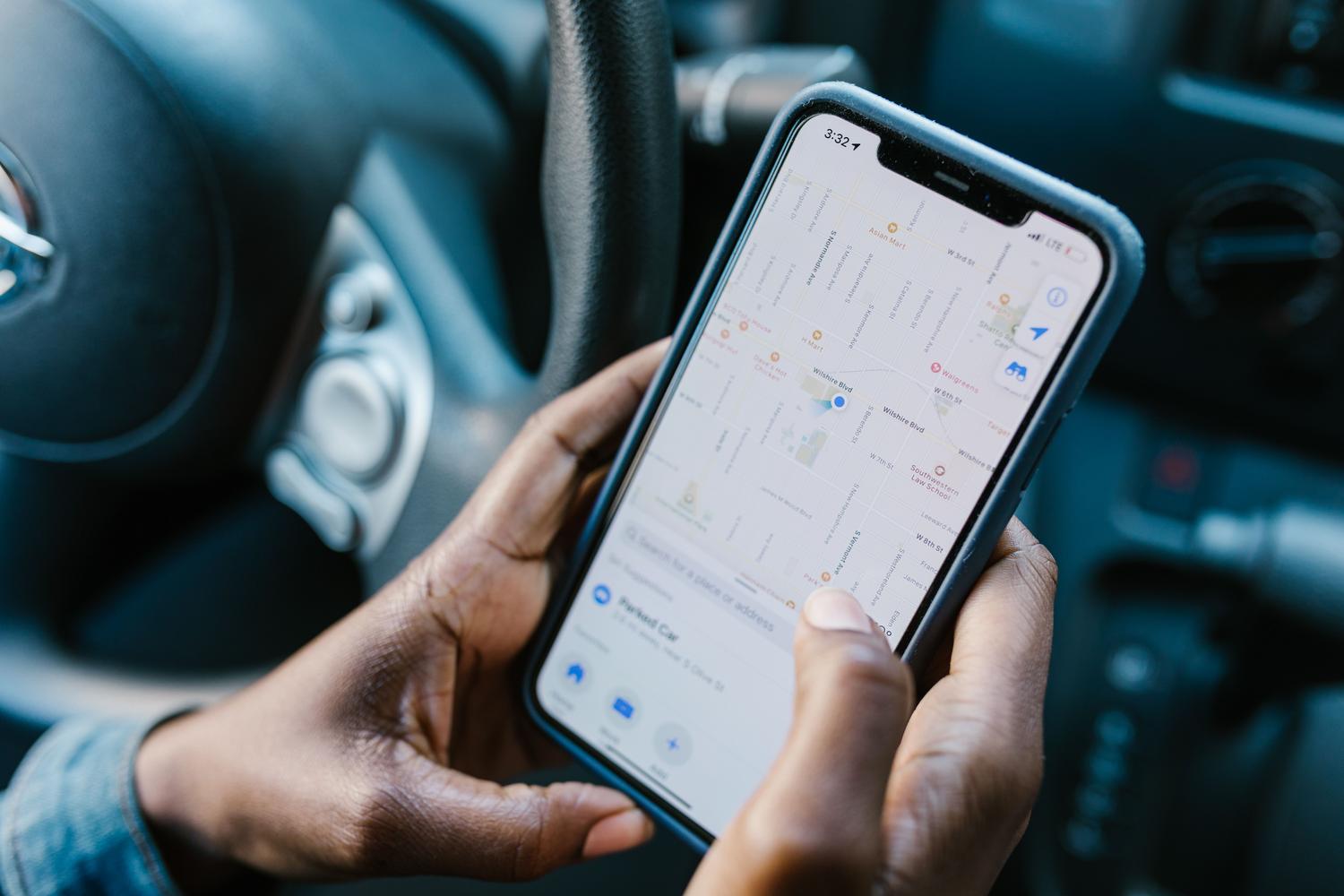 Roku tuvplāns, kas tur iPhone ar lietotni Maps, kas parāda novietotās automašīnas atrašanās vietu. Roku tuvplāns, kas tur iPhone ar lietotni Maps, kas parāda novietotās automašīnas atrašanās vietu.
