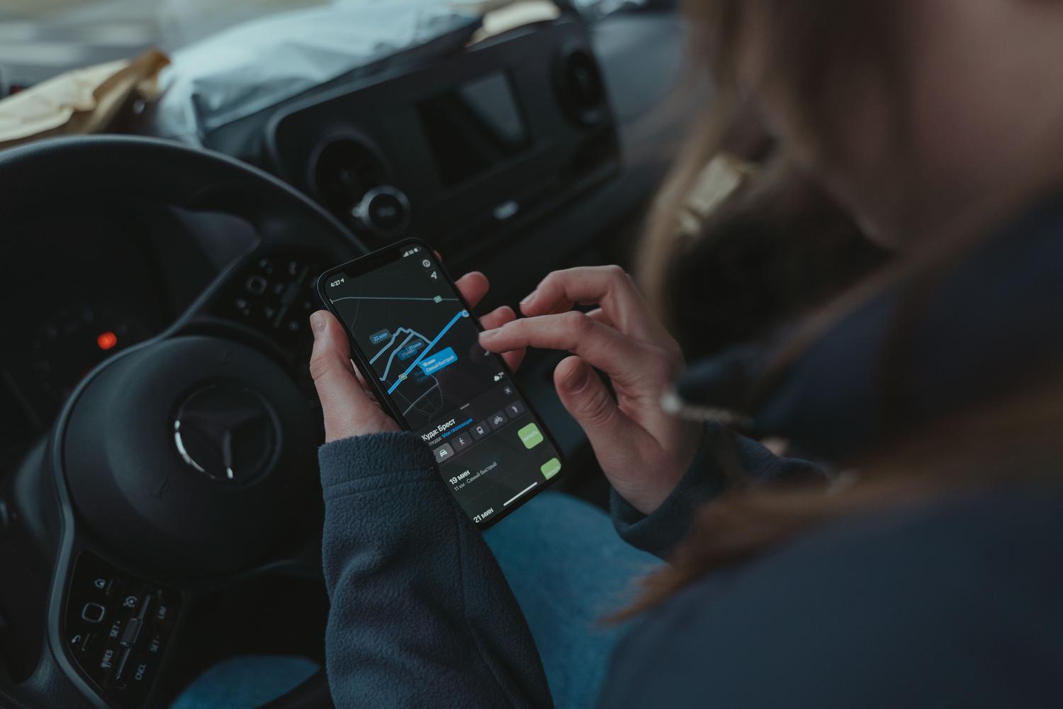 Persona, kas savā viedtālrunī izmanto navigācijas lietotni no transportlīdzekļa iekšpuses, lai atrastu galamērķi. Persona, kas savā viedtālrunī izmanto navigācijas lietotni no transportlīdzekļa iekšpuses, lai atrastu galamērķi.