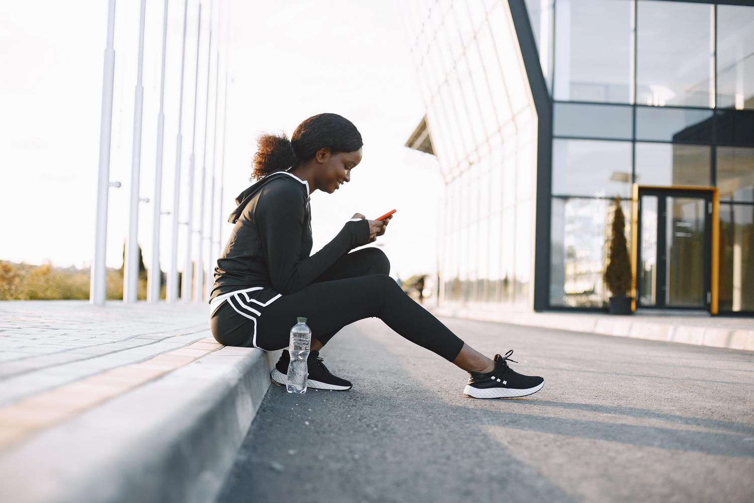 Persona sporta apģērbā un izmanto savu iPhone, lai pārvaldītu sporta rezervācijas. Persona sporta apģērbā un izmanto savu iPhone, lai pārvaldītu sporta rezervācijas.